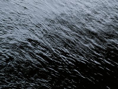 Bottle of water on a black surface with cyan light